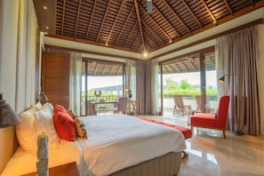 A bedroom with a large bed, a desk, and a chair, and a balcony with a view. - OMEKAI Cemagi by Nakula (Bali)