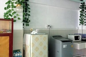 A kitchen with a refrigerator, microwave, and a small cabinet. - Ban Suanlum (Bangkok)
