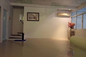 A hallway with a staircase, a radiator, and a window with flowers. - Ban Suanlum (Bangkok)