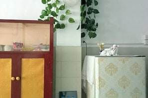 A kitchen with a refrigerator, a cabinet with a glass door, and a plant on the wall. - Ban Suanlum (Bangkok)