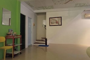 A hallway with a green wall, a door, a staircase, and a framed picture on the wall. - Ban Suanlum (Bangkok)