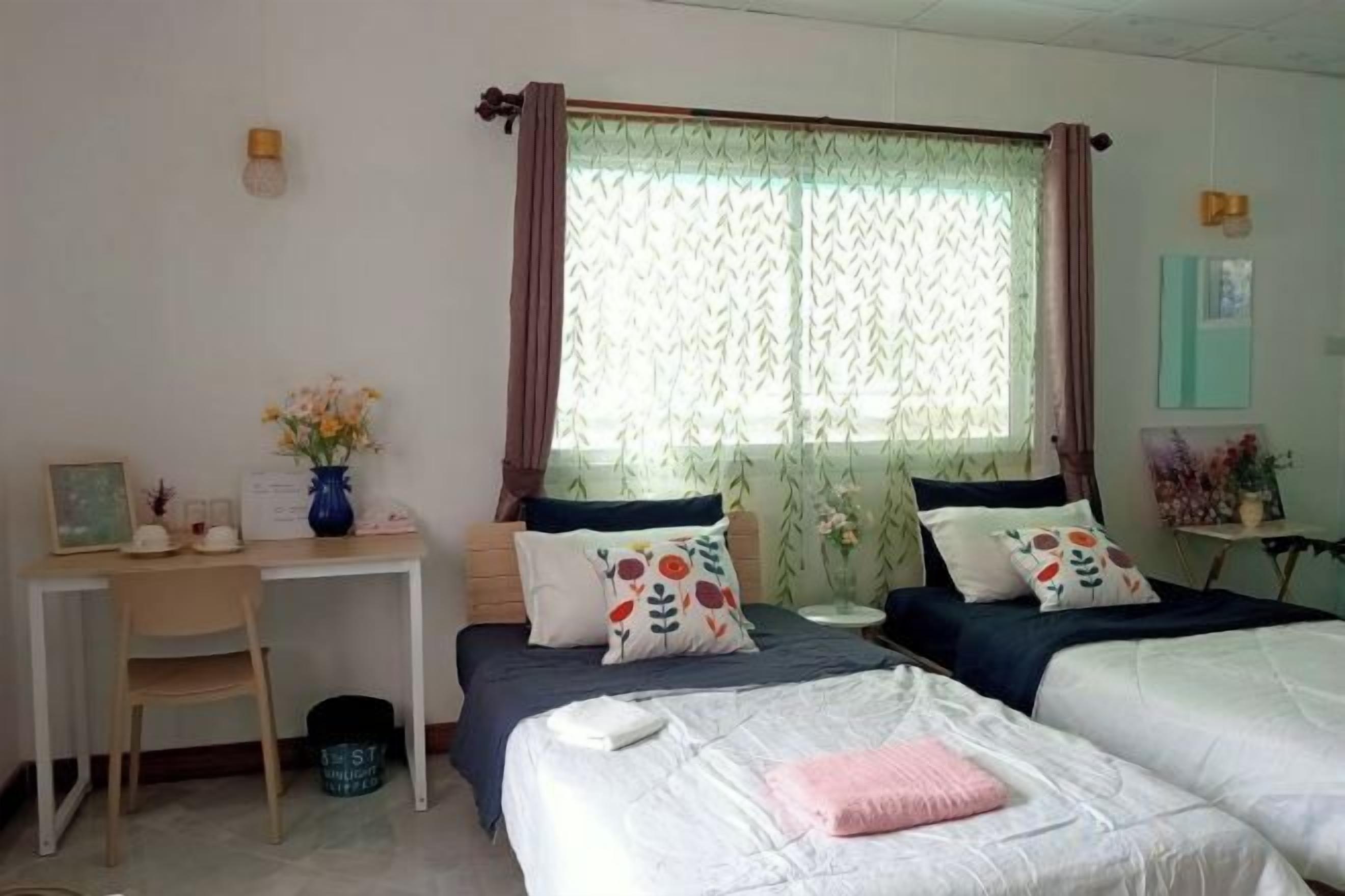 A bedroom with two beds, a desk, and a chair.