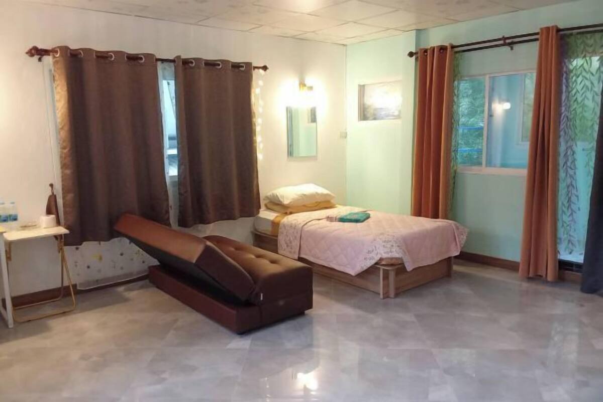 A room with a bed, a bedside table, a bench, and a window with curtains.