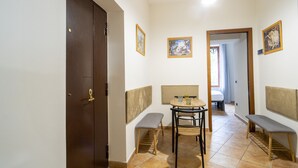 A hallway with a wooden door, a bench, a table with two chairs, and a wall-mounted picture frame. - Dimora Stella by Wonderful Italy (Naples)