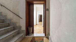 A hallway with a wooden door, a trash bin, and a welcome mat. - Dimora Stella by Wonderful Italy (Naples)