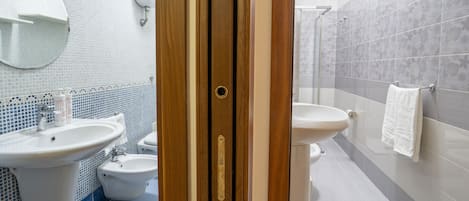 A bathroom with a sink, bidet, and toilet.