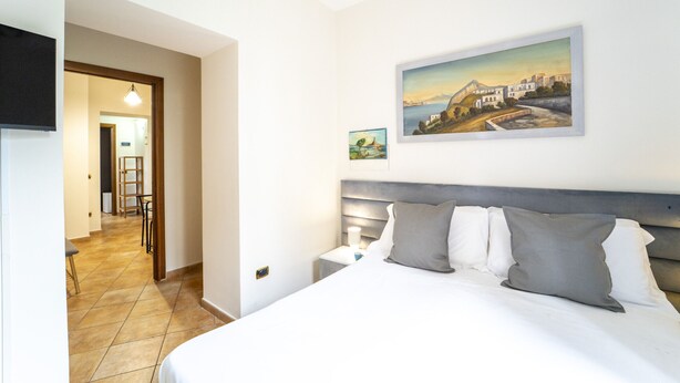 A hotel room with a bed, a nightstand, a painting, and a television on the wall. - Dimora Stella by Wonderful Italy (Naples)