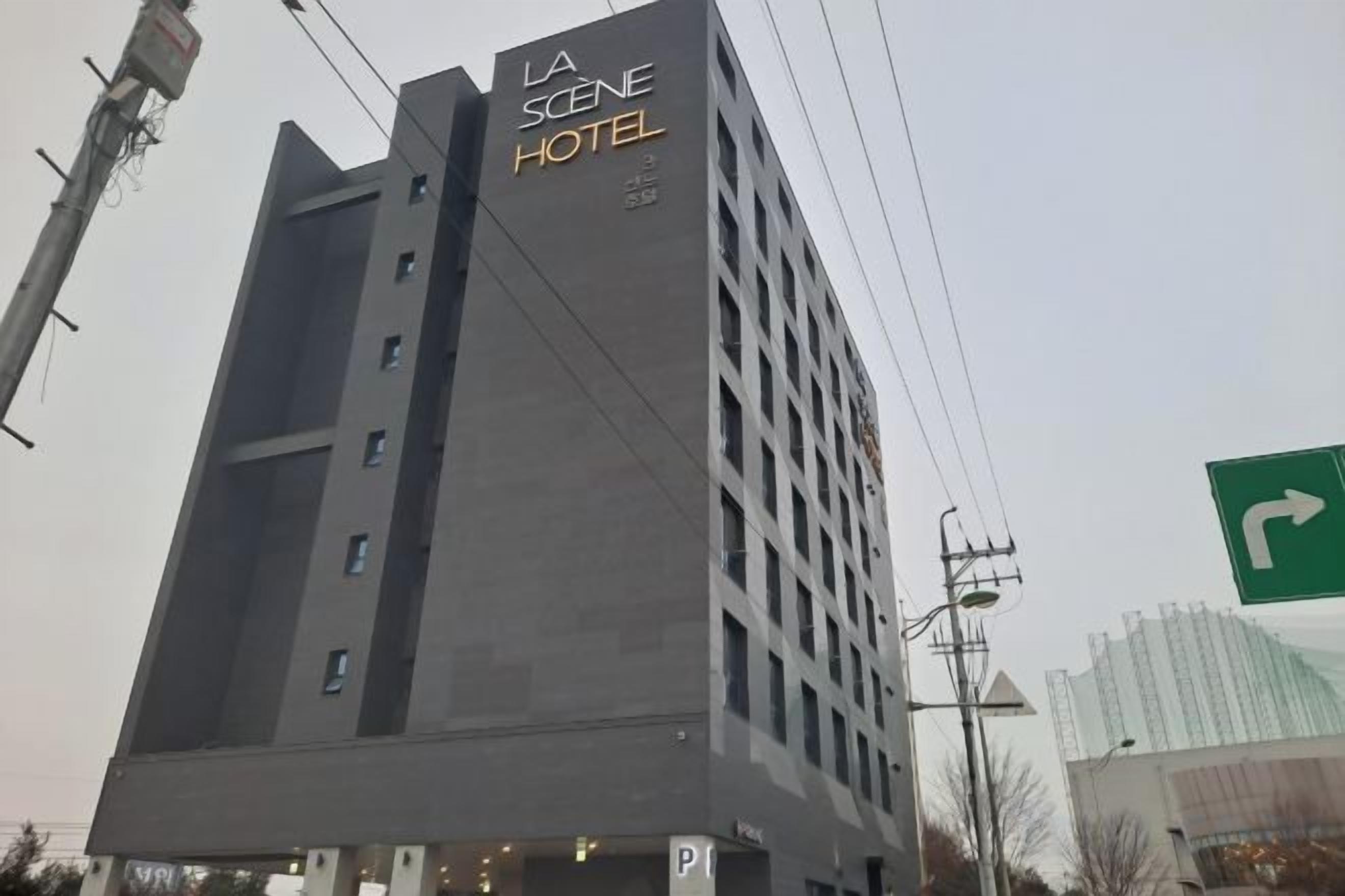 Un edificio alto con el letrero 'LA SCENE HOTEL' en la fachada.