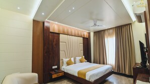 Una habitación de hotel con cama, escritorio, silla, televisor y ventilador de techo.