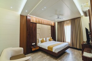 Une chambre d’hôtel équipée d’un lit, d’un bureau, d’une chaise, d’une télévision et d’un ventilateur de plafond.