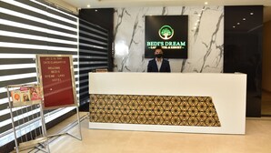 Un mostrador de recepción con una pared de mármol y un cartel que indica 'Bedi's Dream Land Hotel'.