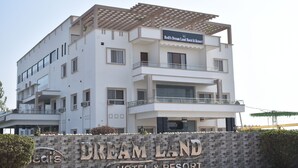 Un hotel de varios pisos con un letrero que dice 'Bedit's Dream Land Hotel & Resort' y un muro de piedra con el nombre del hotel.