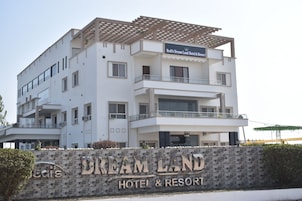 Um hotel de vários andares com uma placa que diz 'Bedit's Dream Land Hotel & Resort' e uma parede de pedra com o nome do hotel.