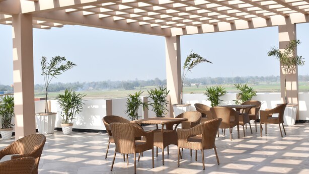 Un espacio de estar al aire libre con techo, mobiliario de mimbre y plantas en macetas, con vistas a un paisaje pintoresco.