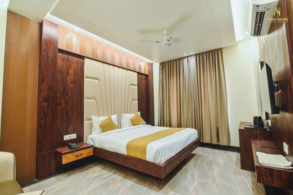 Quarto de hotel com cama, mesa de cabeceira e ventilador de teto.