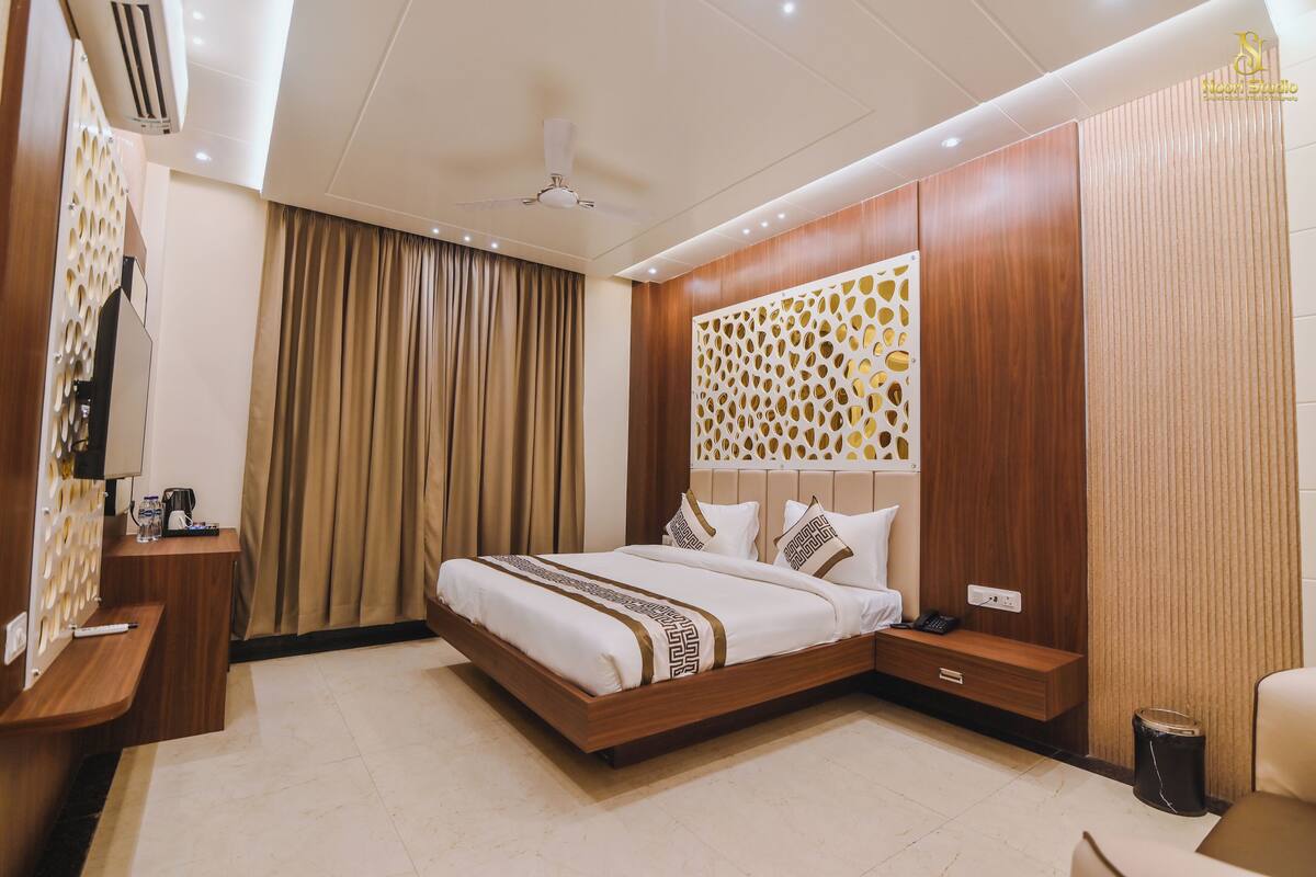 Quarto de hotel moderno com uma cama grande, uma escrivaninha, uma cadeira, uma TV e um painel decorativo na parede.