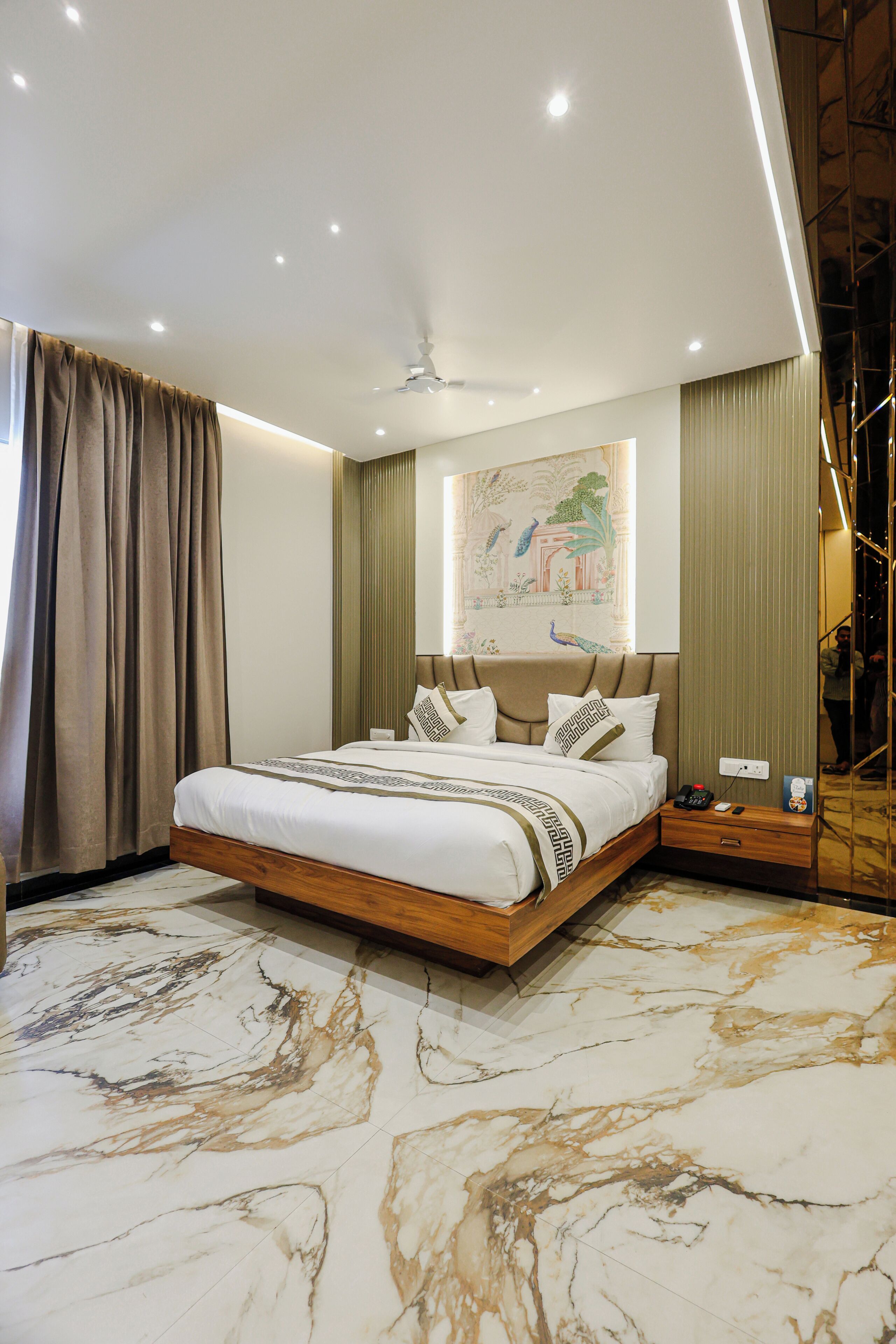 Una habitación de hotel moderna con una cama grande, un ventilador de techo y suelo de mármol.
