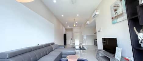 A modern living room with a grey sectional sofa, a flat-screen TV, and a ceiling fan.