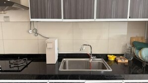 A kitchen with a black countertop, stainless steel sink, and grey cabinets. - The Loft Imago Shopping Mall By Chill Time (Kota Kinabalu)