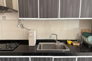 A kitchen with a black countertop, stainless steel sink, and grey cabinets. - The Loft Imago Shopping Mall By Chill Time (Kota Kinabalu)