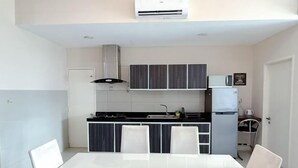 A modern kitchen with a dining table and chairs, a microwave, and a refrigerator. - The Loft Imago Shopping Mall By Chill Time (Kota Kinabalu)