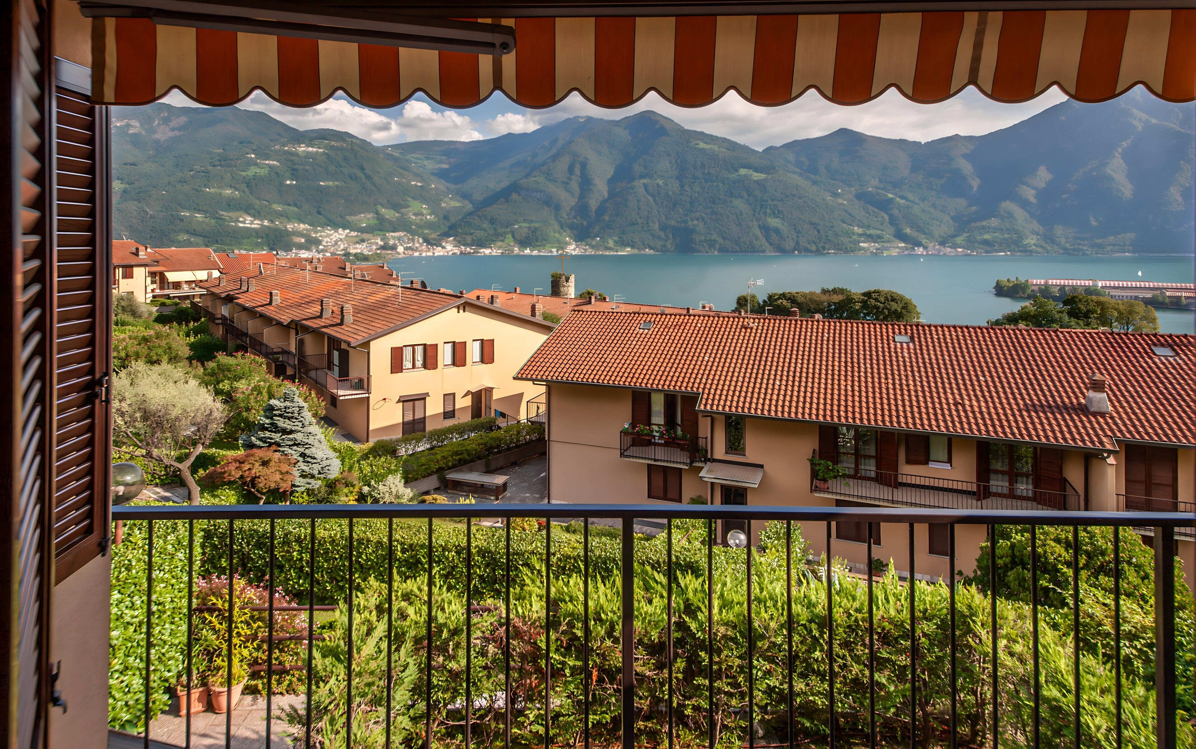 Un balcon avec vue sur une ville, des montagnes et un lac.