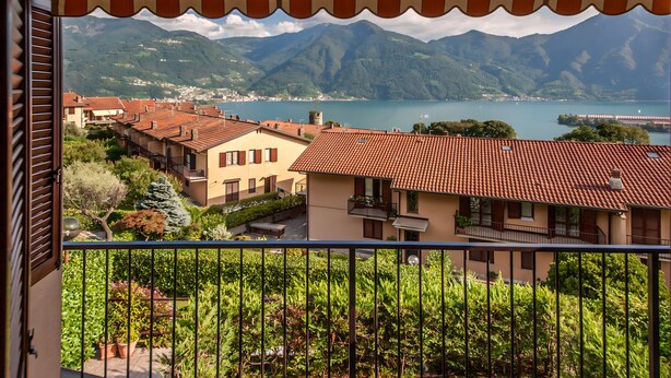 Ein Balkon mit Blick auf eine Stadt, Berge und einen See.