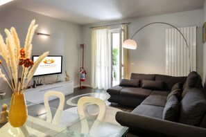 Ein modernes Wohnzimmer mit einer Couch, einem Glastisch und einer Vase mit Pampasgras.