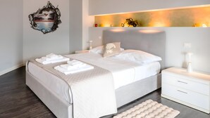Ein modernes Schlafzimmer mit einem großen Bett, einem mit Beleuchtung versehenen Kopfteil, einem Nachttisch mit Lampe und einem Wandbild.