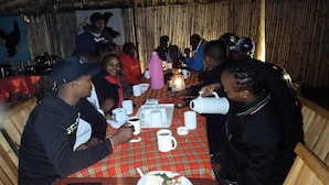 A group of people seated around a table with a red and green checkered tablecloth, engaged in conversation. - Blue Zone Kenya Resorts and Game Drives (Nanyuki)