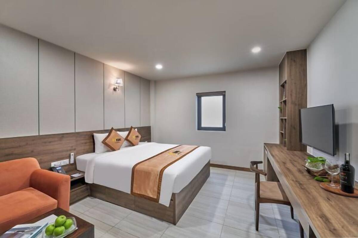 Una habitación de hotel con cama, un escritorio de madera, televisor y ventana.
