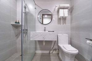 A modern bathroom with a glass-enclosed shower, a marble sink, and a toilet. - Bcons PS Bien Hoa Hotel (Bien Hoa)