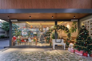 A modern building entrance with a glass facade, a wooden ceiling, and a Christmas tree decorated with ornaments. - Bcons PS Bien Hoa Hotel (Bien Hoa)
