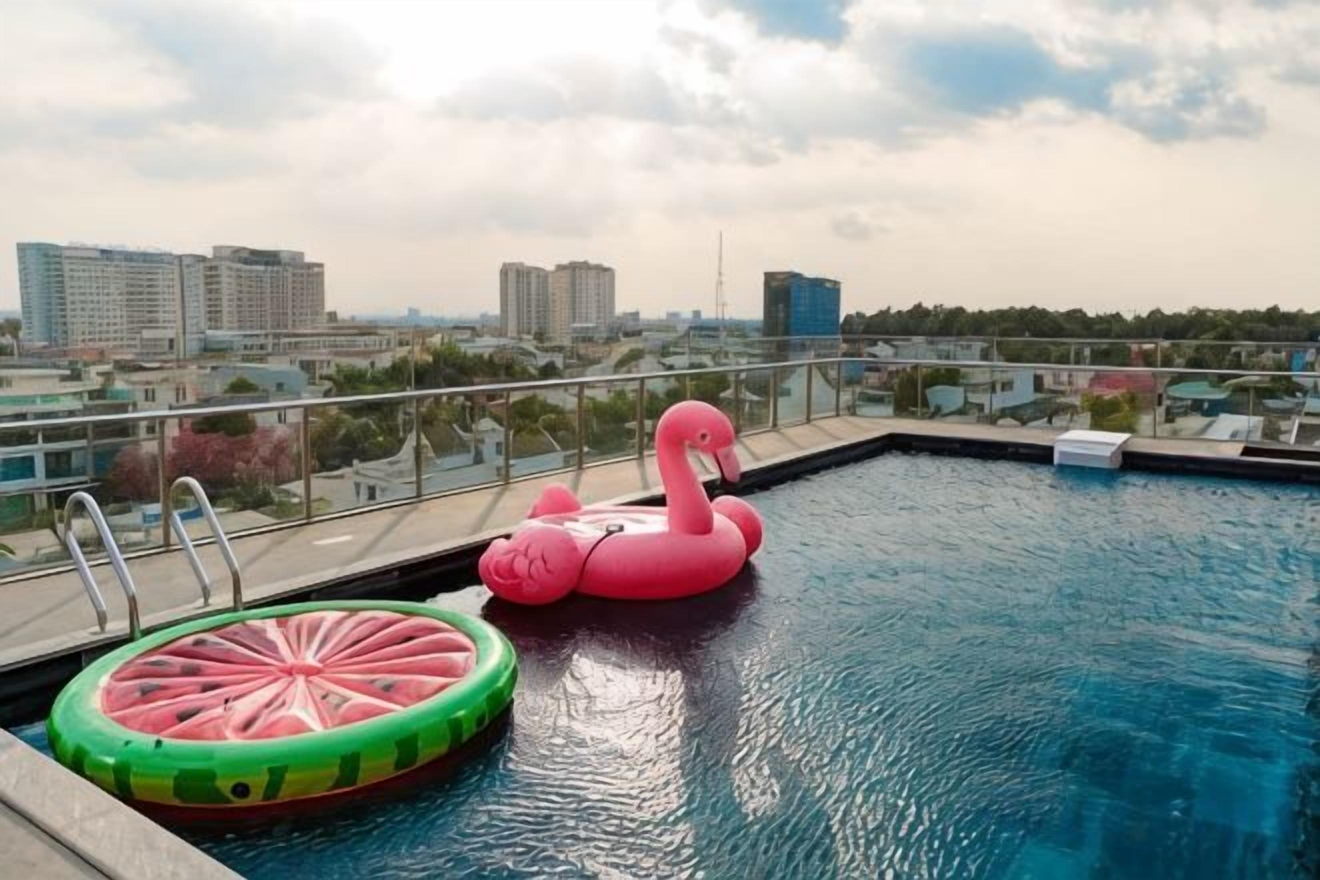 A swimming pool with a pink flamingo float and a watermelon float.