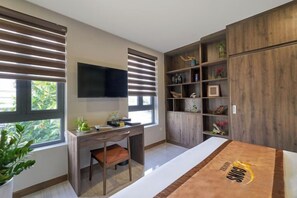 A modern room with a desk, chair, TV, bookshelf, and a large wooden cabinet. - Bcons PS Bien Hoa Hotel (Bien Hoa)