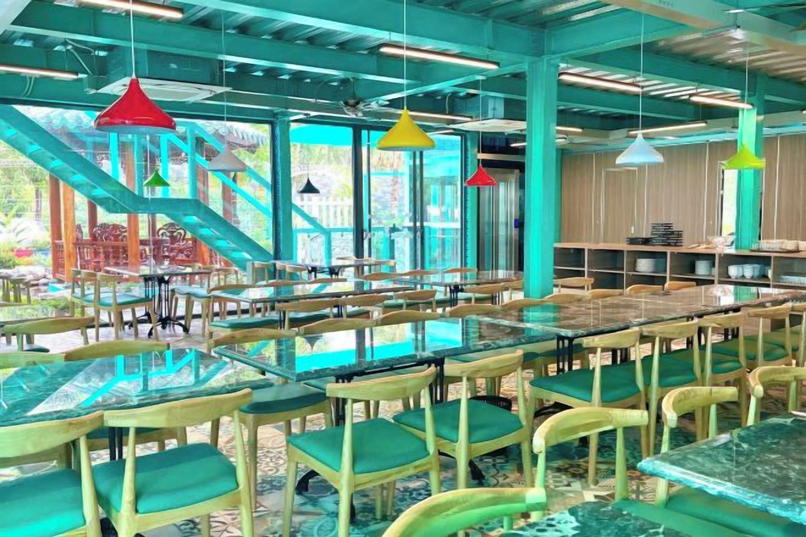 Un restaurante con terraza, ventanas amplias y vistosas lámparas colgantes.