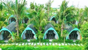 Una hilera de cabañas con forma de cúpula y techos curvos, rodeadas de abundante vegetación y palmeras.