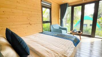A wooden-paneled room with a bed, a chair, and a table.