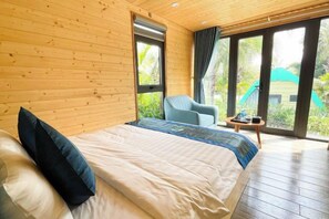 Ein Zimmer mit Holzwänden, einem Bett, einem Sessel und einem Tisch.
