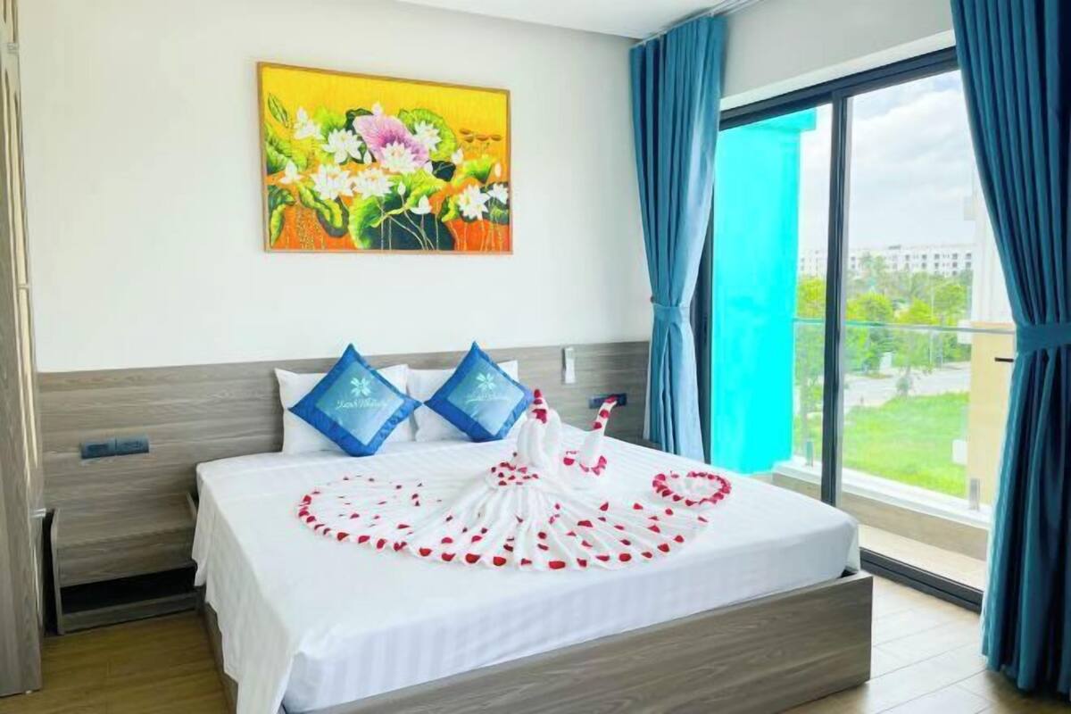 Una habitación de hotel con una cama, un cuadro en la pared y vistas a través de la ventana.