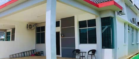 A modern house with a covered patio, large windows, and a red roof.