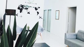 A modern hotel lobby with a world map mural, a grey sofa, and a large plant. - D' Splash Garden Homestay Baling (Baling)