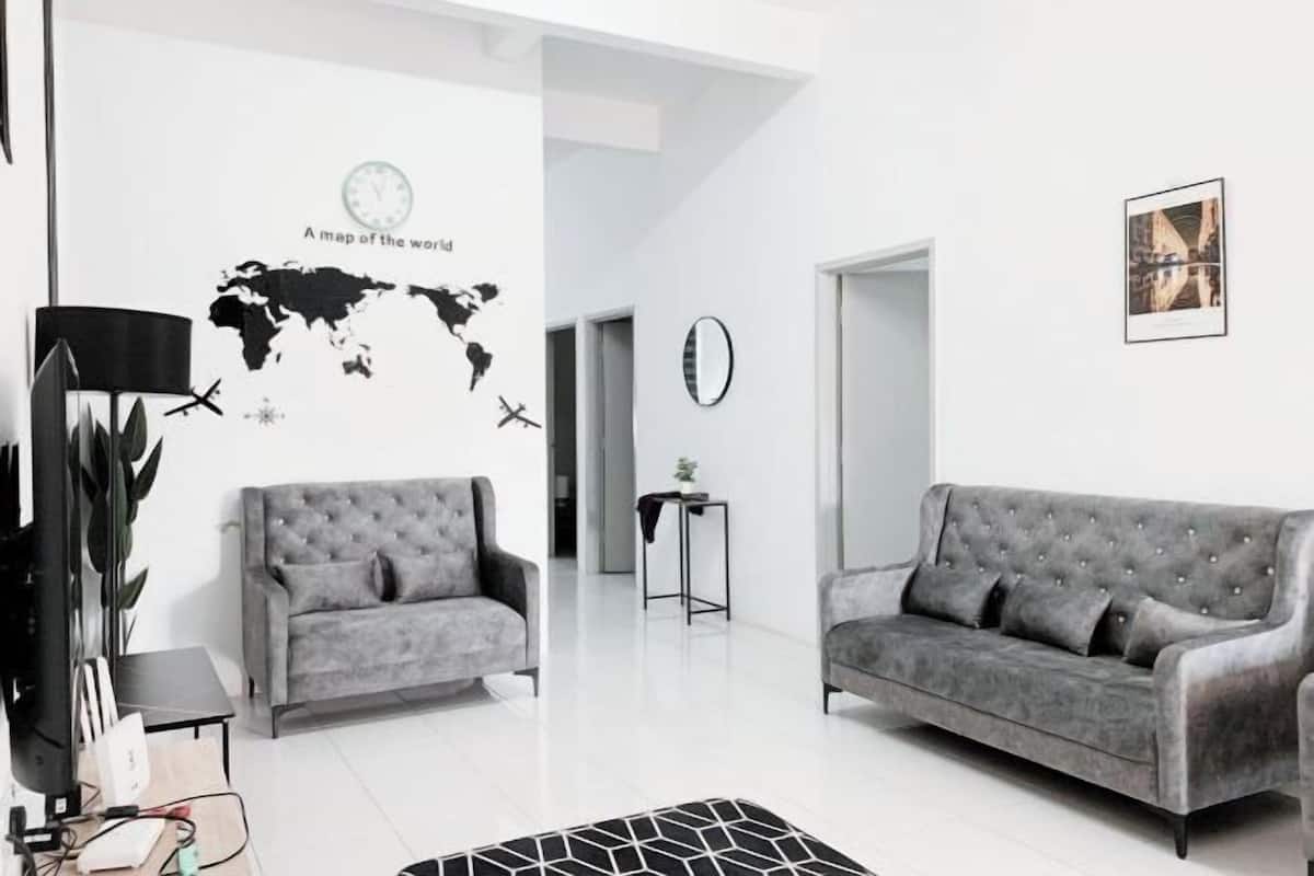 Una sala de estar moderna con dos sofás grises, un cuadro mural de un mapa del mundo, un reloj y un cuadro enmarcado en la pared.