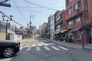 Une vue de rue avec des immeubles, un passage piéton et une voiture garée.