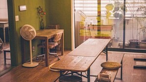 Ein Zimmer mit einem Holztisch, einem Ventilator und einem Fenster mit Jalousien.