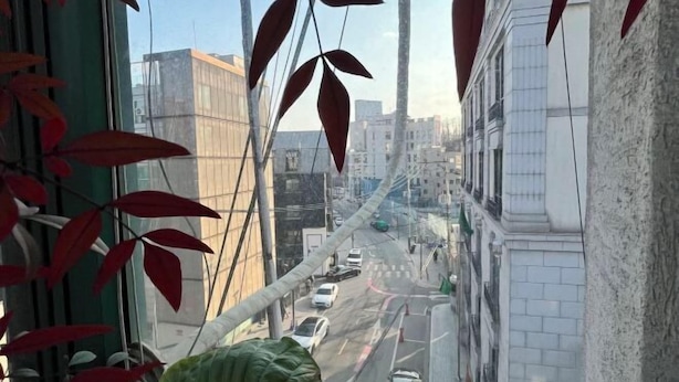 Blick aus einem Fenster auf eine Stadtstraße mit Gebäuden und Fahrzeugen.