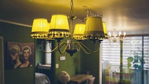 Ein Kronleuchter mit mehreren Lampen, ein Esstisch, Stühle und ein Gemälde an der Wand.