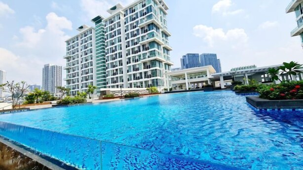 A modern hotel with a large swimming pool, surrounded by high-rise buildings and greenery.