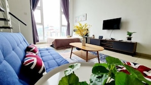 A modern living room with a blue sofa, a small round table, a TV, and a plant.