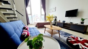 A modern living room with a blue sofa, a round coffee table, and a television mounted on the wall.